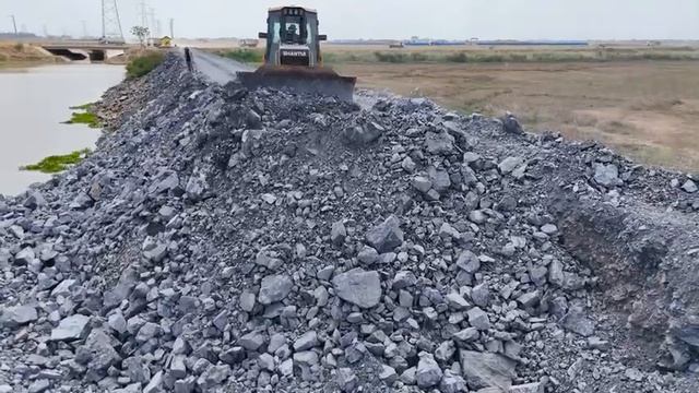 Replenishing stone on damaged road surfaces, bulldozer push stone and dump truck transport the stone смотреть онлайн
