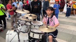 Китайская Девочка игает на барабанах на улице
