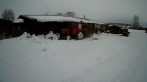 Расчистка снега от сеновала, нужно завозить сено. Минитрактор на цепях расталкивает слежавшийся снег
