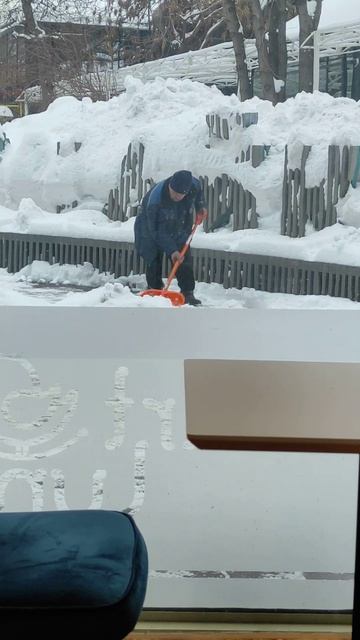 Уставший дворник убирает снег.