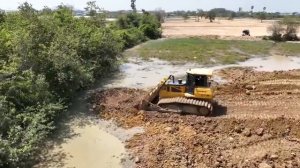 Первый самосвал NISSAN Загружает грунтовую породу, заполняя земельный участок, Бульдозер выталкивает