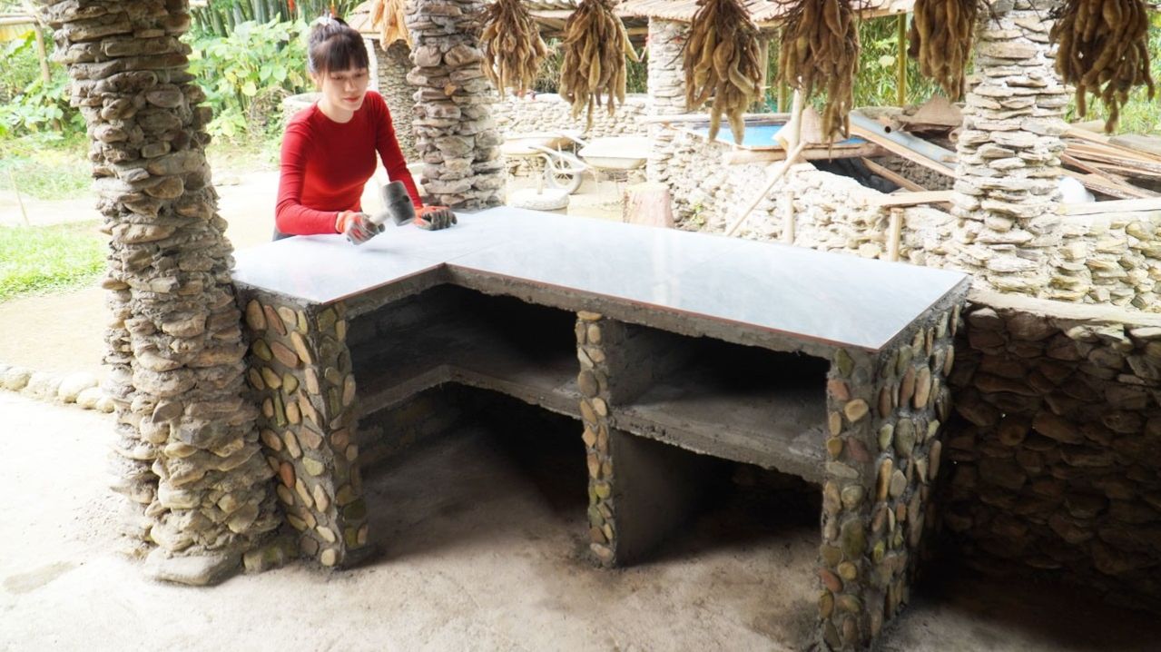 Молодая женщина построила кухню из кирпичей. Строительства кухонного стола в традиционном стиле