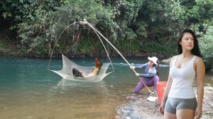 Девушка ловит рыбу в ручье. Традиционная рыбалка траловыми сетями. Ловит много крупной рыбы
