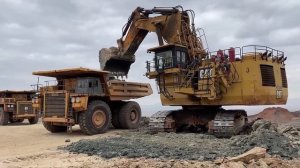 Огромный карьерный экскаватор Caterpillar 6040 Загружает самосвалы Hitachi EH3500