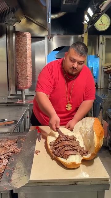 Толстый мужчина делает себе большой бургер из батона