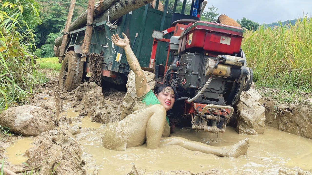 Сельскохозяйственная техника перевозит древесину по очень сложным грунтовым дорогам, покрытым грязью
