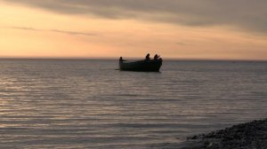 Работа рыбаков в лодке на закате.