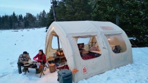 Кемпинг в заснеженном лесу, с надувной палаткой.