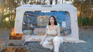 Кемпинг девушки в лесу в прозрачной надувной и тёплой палатке.