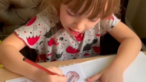 Арина разукрашивает буквы и слова букваря-разукрашки