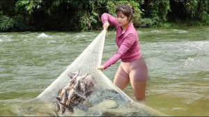 Девушка закидывает сеть, чтобы поймать рыбу в реке. Большой улов рыбы. Жизнь во Вьетнаме