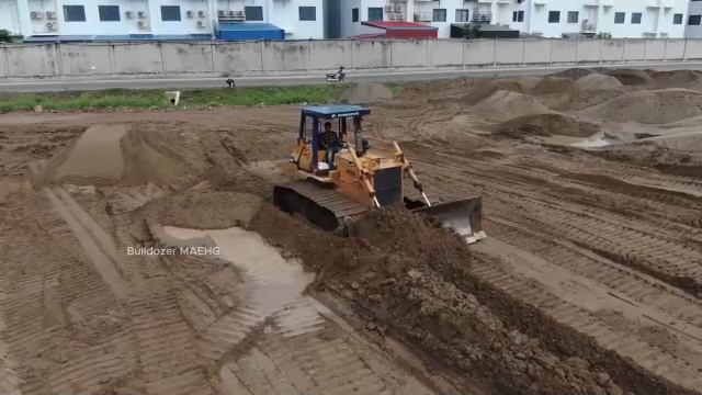 Экскаватор-бульдозер засыпает болото песком и специальной смесью.