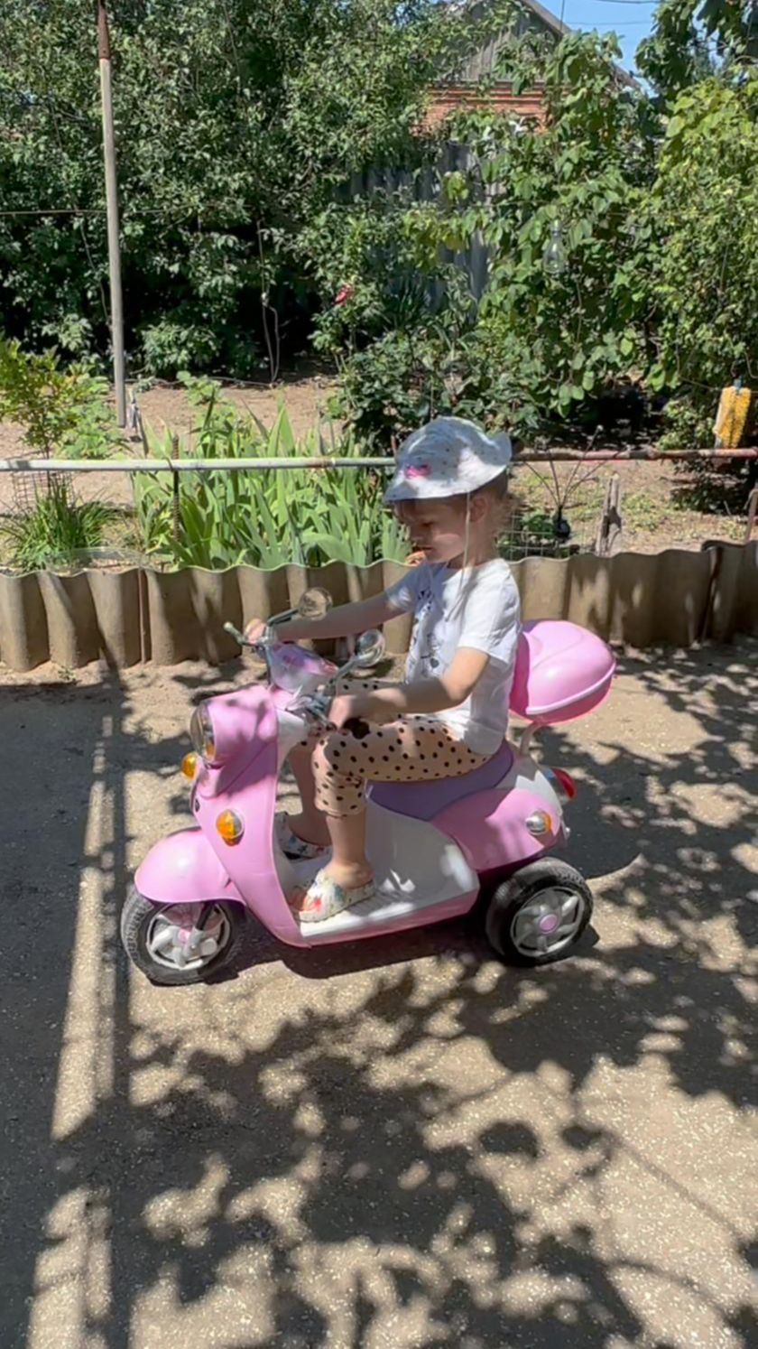 Арина катается на мопеде по двору на хуторе у бабушки