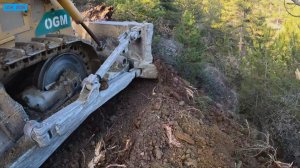 Бульдозер Cat D7G прокладывает дорогу на почти отвесном склоне горы.