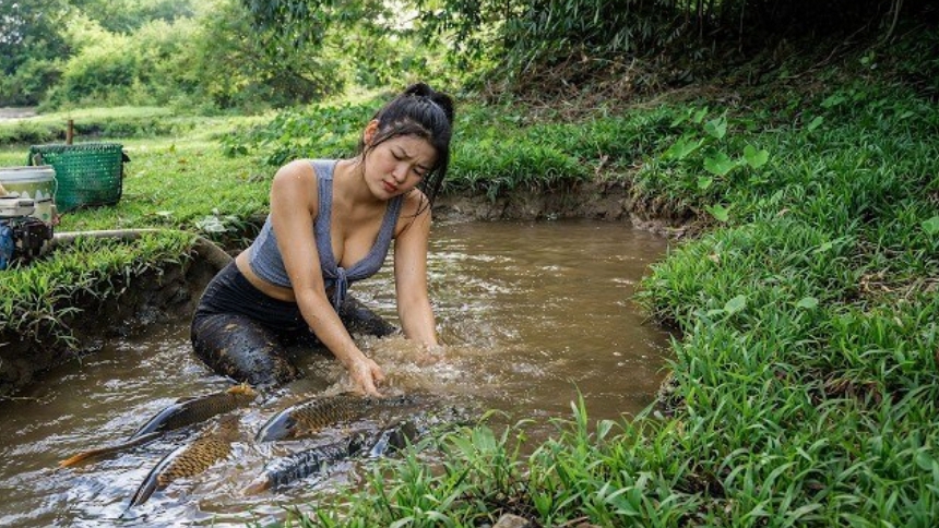 Девушка ловит рыбу руками. Примитивная техника выживания.