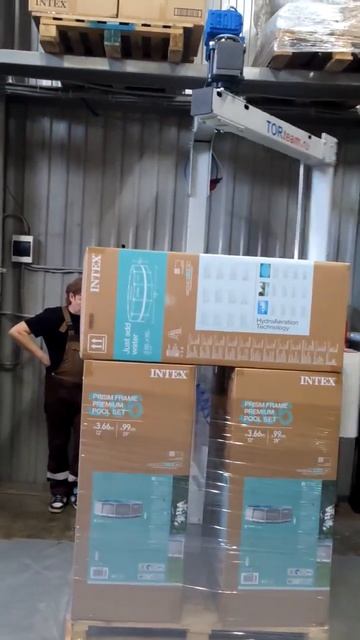 Упаковочная рука в работе. Паллеты с коробками