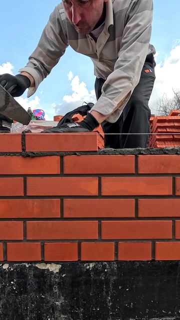 Процесс кладки лицевого кирпича, строительство кирпичного дома.