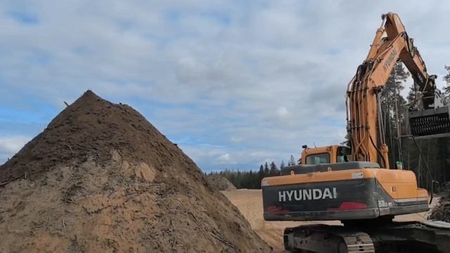 Просеивающий ковш для добычи чернозёма из вскрышных пород в лесу. Он разделяет корневища и чернозем