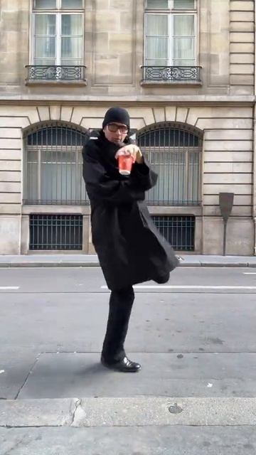 Мужчина в длинном черном пальто в черной шапке со стаканом кофе держит стаканчик смешно ходит  #мем