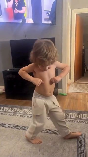 Маленький мальчик с длинными волосами танцует без футболки