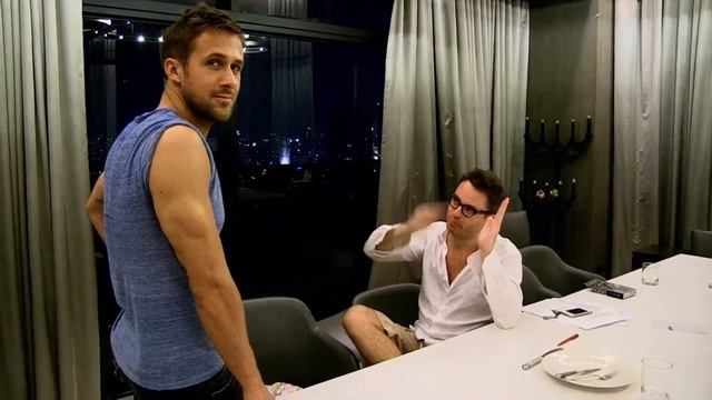 Мужчина Райан Гослинг в синей футболке разговаривает с мужчиной оборачивается смотрит в камеру