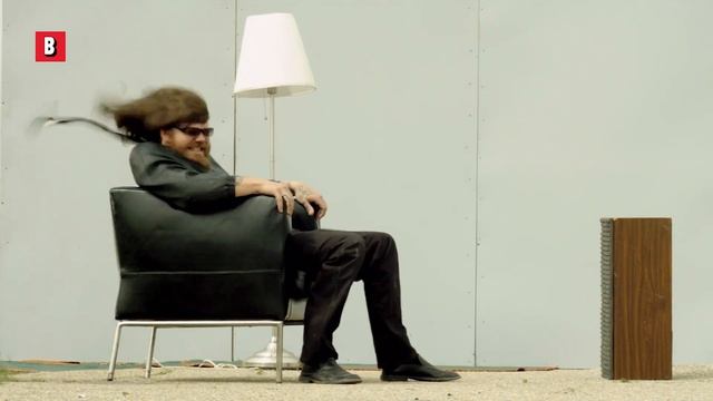 Мужчина сидит в кресле на улице его сдувает сильным ветром