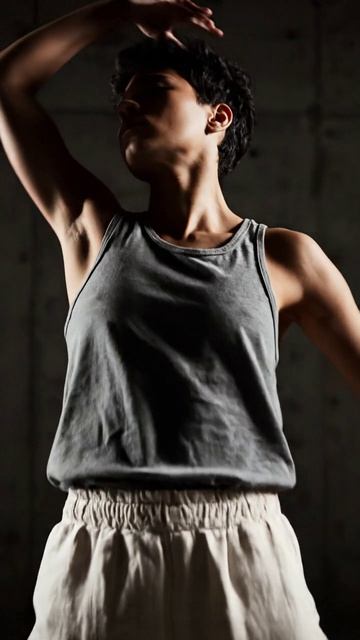 Танцовщица исполняет плавные движения на фоне бетонной стены под минимал‑#техно