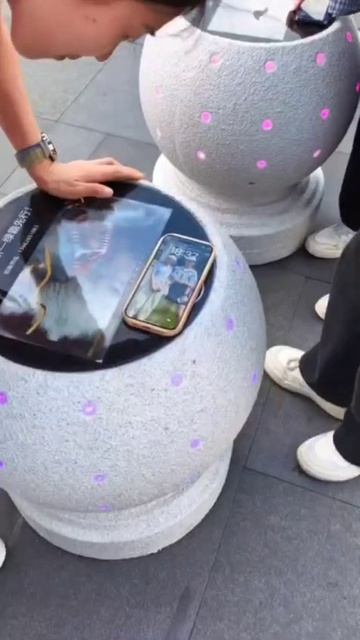 Люди заряжают свои мобильные телефоны с помощью умных каменных столбов в районе Лунхуа