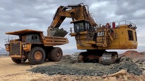 Огромный карьерный экскаватор Caterpillar 6040 Загружает самосвалы Hitachi EH3500