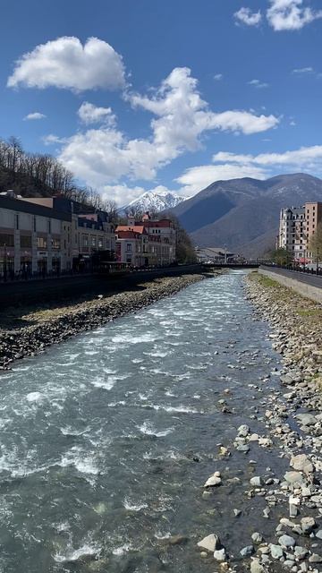 Гармоничный и прекрасный вид реки и гор в окружении домов.