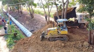 Bury drainage system by mini dozer pushing soil with dump trucks upload