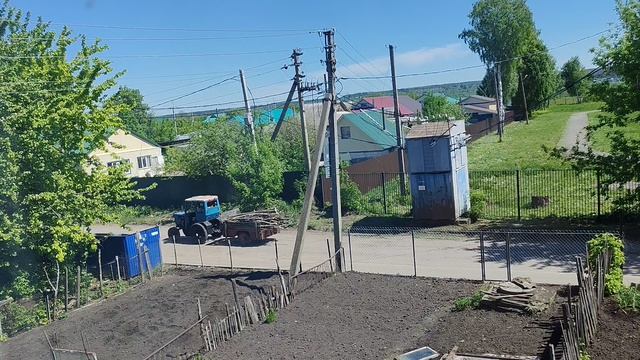трактор едет по дороге в деревне