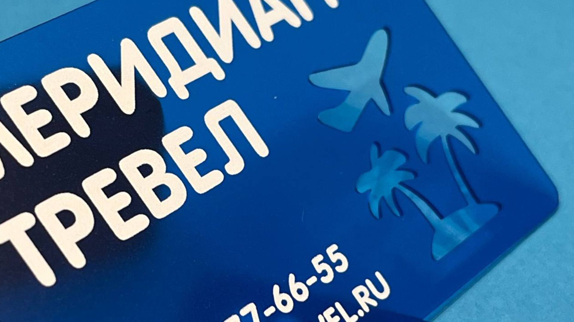 Визитка туристического агентства на прозрачном синем пластике с фигурной вырезкой пальмы и самолёта