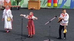 Поющая девочка исполняет частушки. Мужчина-аккомпаниатор подыгрывает на балалайке.