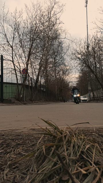 Скутер навстречу камере. Фары мерцают, проезжаю мимо на закате