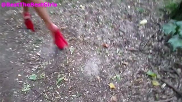 Девушка в красных босоножках на высоком каблуке идет по лесной тропинке. Превью