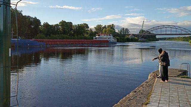 Юная рыбачка ловит рыбку на канале, а пароход идёт