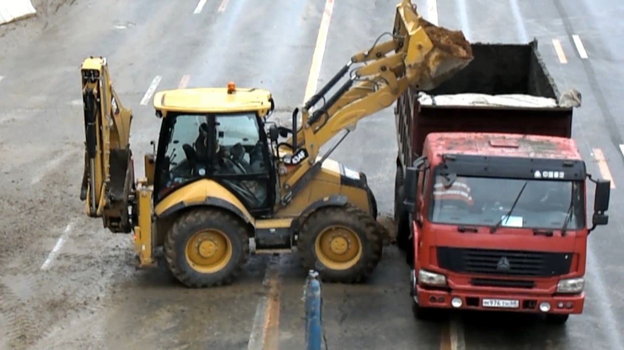 Экскаватор-погрузчик Cat 434F грузит самосвал