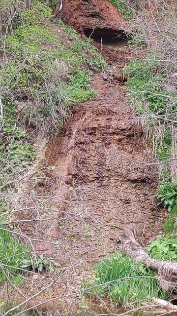 Красный водопад бьет из скалы на берегу реки