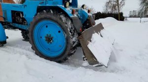 Трактор МТЗ-82 толкает снег.