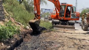 Excavator Cleaning A Trench In The Road Side