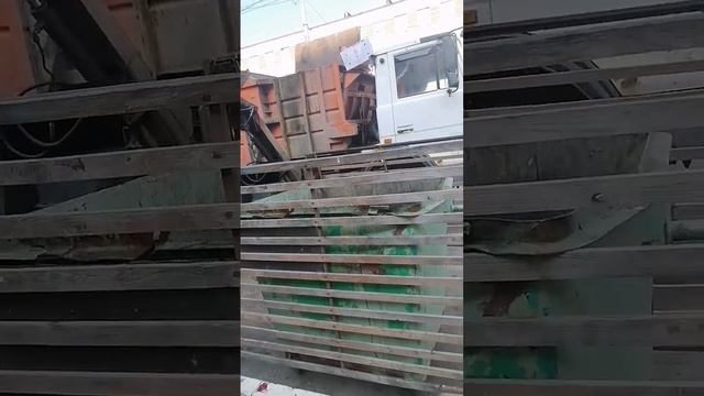 Ловкая работа водителя мусоровоза по очистке мусорных баков на территории овощного рынка.