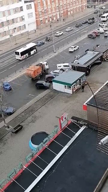 Мусоровоз на парковке продовольственного рынка.