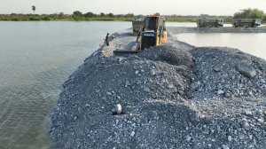 Process Nicely!! A truck transporting rocks into the lake with a bulldozer pushing them expertly