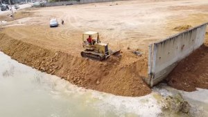 Small Dozer Pushing Soil Filling Lake With Many 5T Dump Trucks
