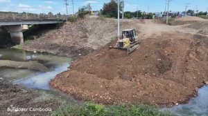 Мощный бульдозер Komatsu сдвигает грунт в воду для прокладки новой дороги