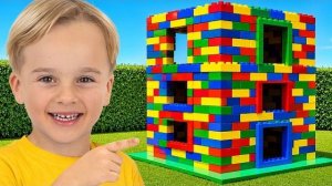 Дети играют с цветными игрушечными кубиками и строят трехэтажный дом