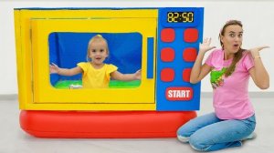 Алиса и мама играют с игрушечной микроволновкой
