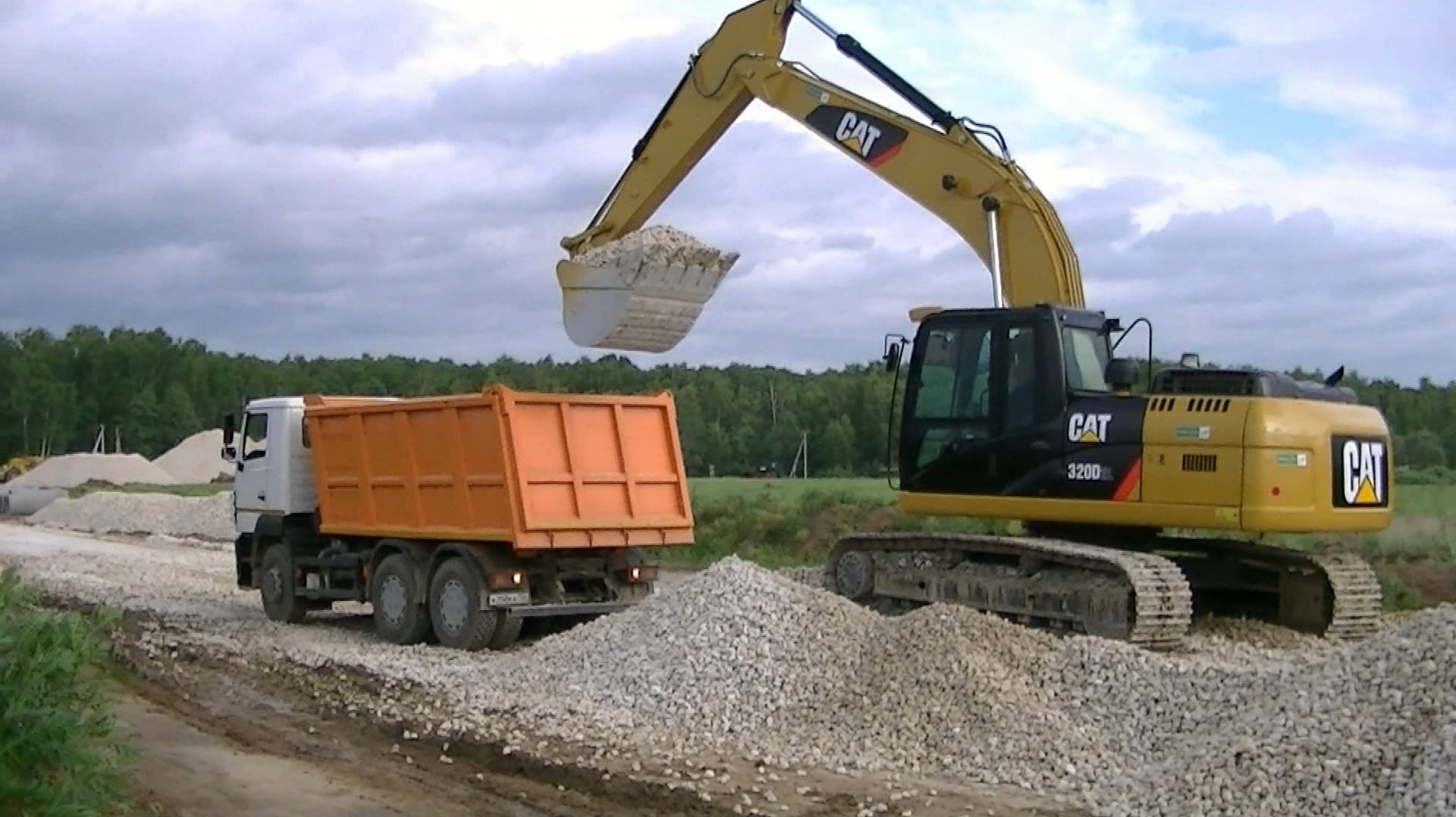 Экскаватор Cat 320D2 L грузит самосвалы МАЗ