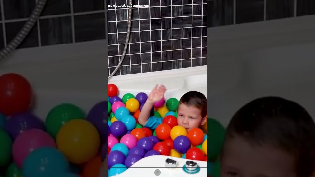 A Child Plays In The Bathtub With Red Balls